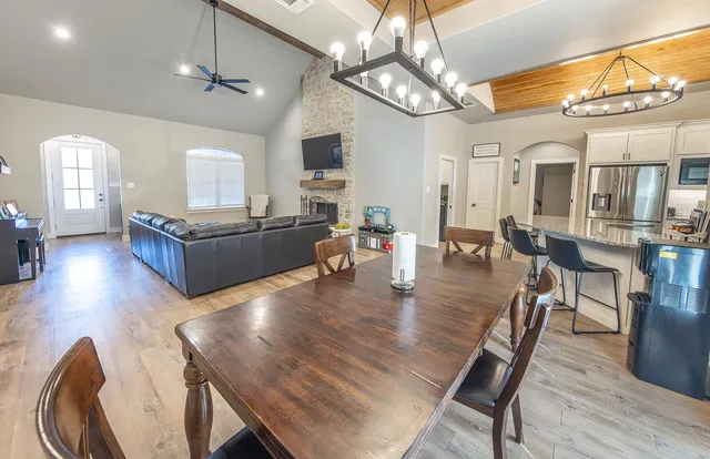 a dining room with wooden floor a chandelier a wooden table and chairs