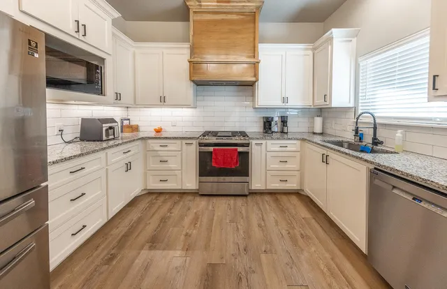 a kitchen with stainless steel appliances granite countertop wooden cabinets and sink