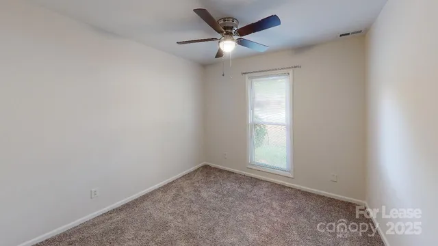 an empty room with a window and a fan