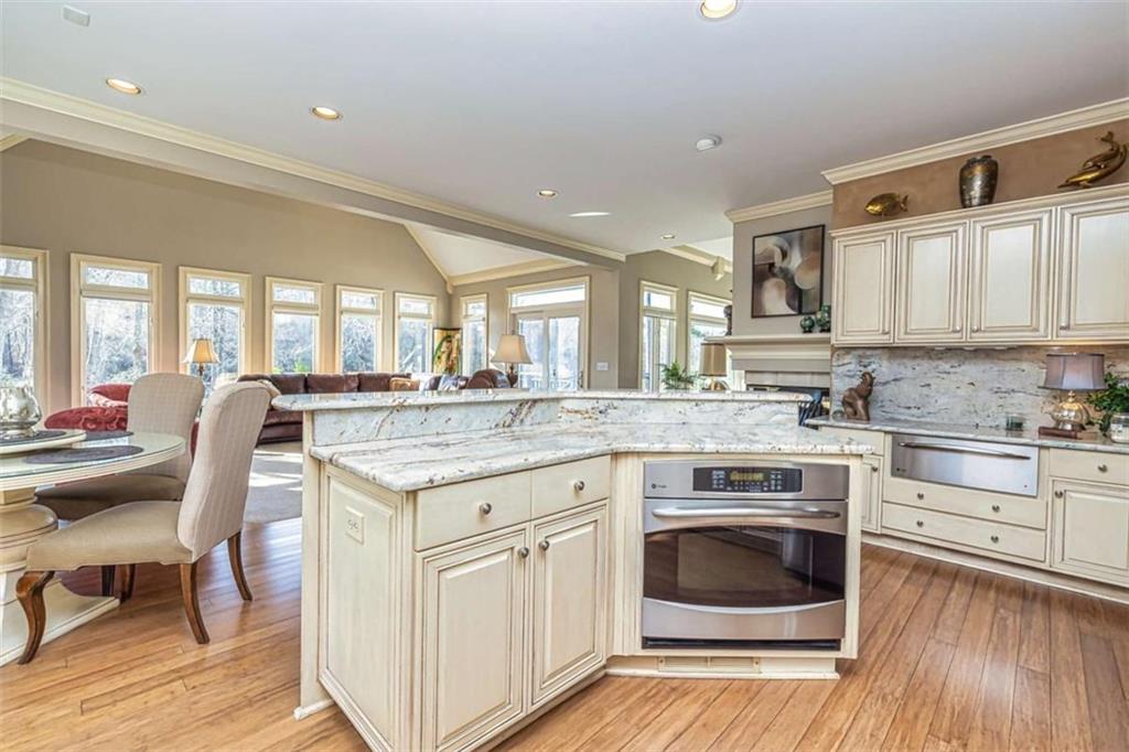35 Torrey Pines Court Newnan, GA 30265 - Photo 25 of 54 a open kitchen with granite countertop a stove top oven a sink dishwasher and white cabinets with wooden floor