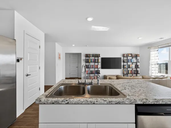 a kitchen with granite countertop a sink and a refrigerator
