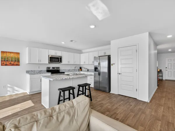 a kitchen with stainless steel appliances kitchen island granite countertop a refrigerator and microwave