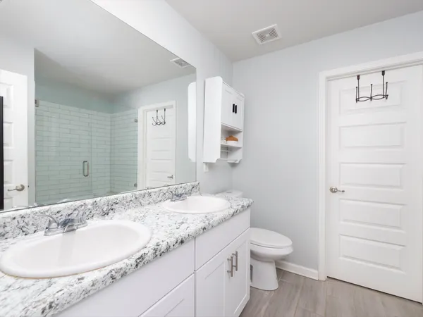 a bathroom with a granite countertop sink toilet a large mirror and shower