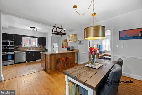 a kitchen with a stove a refrigerator and a dining table with wooden floor