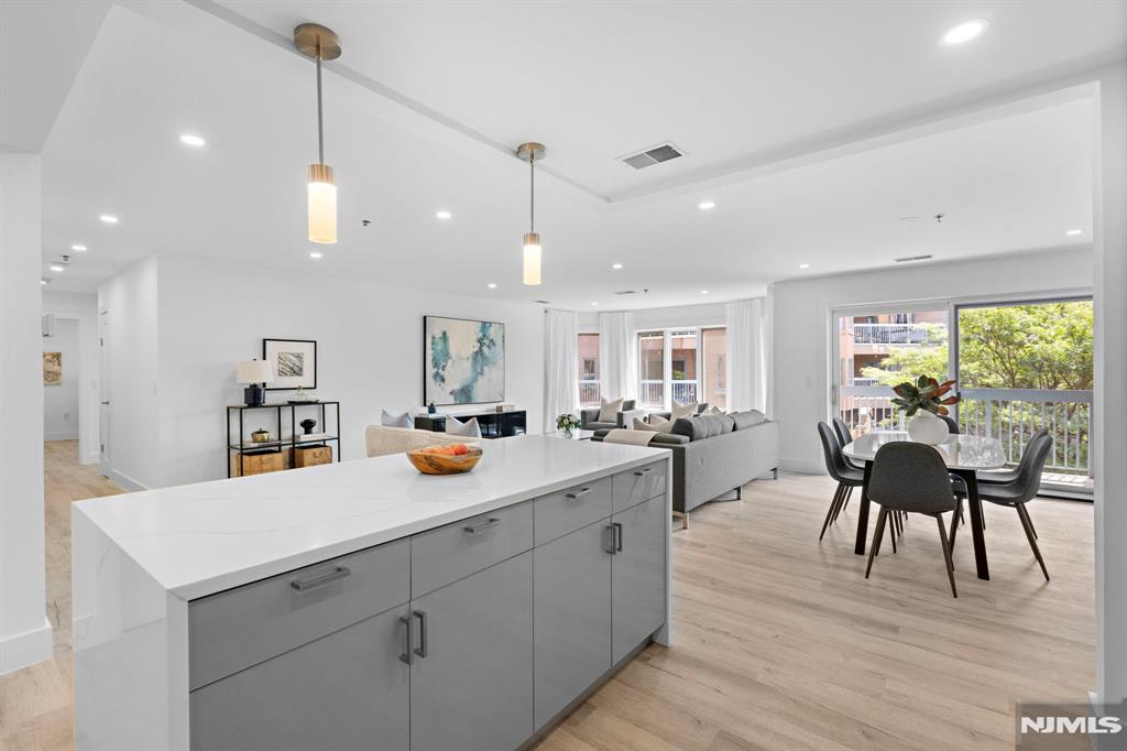 302 Smith Court Edgewater, NJ 07020 - Photo 13 of 34 a view of a dining room and livingroom with furniture wooden floor a rug a rug a flat screen tv a painting and a chandelier