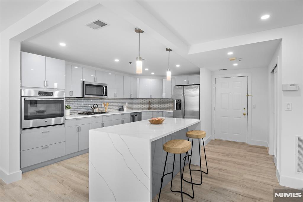 302 Smith Court Edgewater, NJ 07020 - Photo 15 of 34 a kitchen with stainless steel appliances kitchen island granite countertop a wooden floor and white cabinets