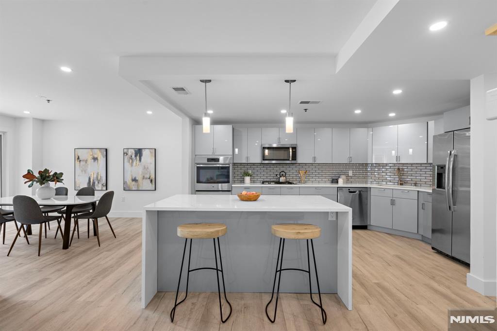 302 Smith Court Edgewater, NJ 07020 - Photo 3 of 34 a kitchen with a dining table chairs wooden floor cabinets and stainless steel appliances