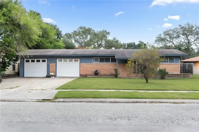 a front view of a house with a garden and parking