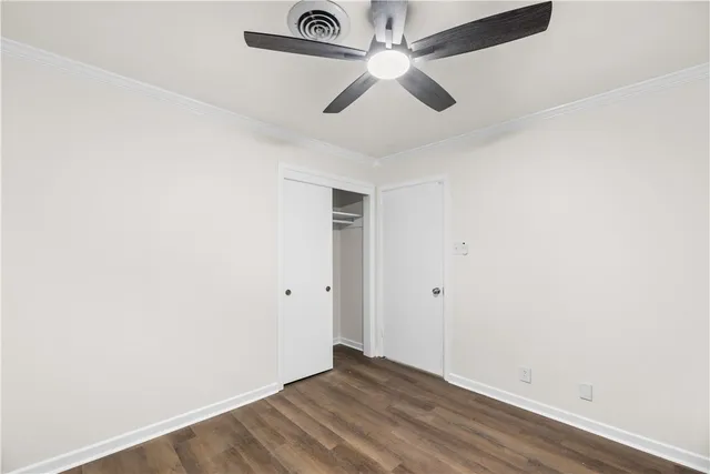 an empty room with a ceiling fan and wooden floor