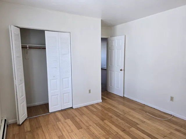 an empty room with closet and wooden floor