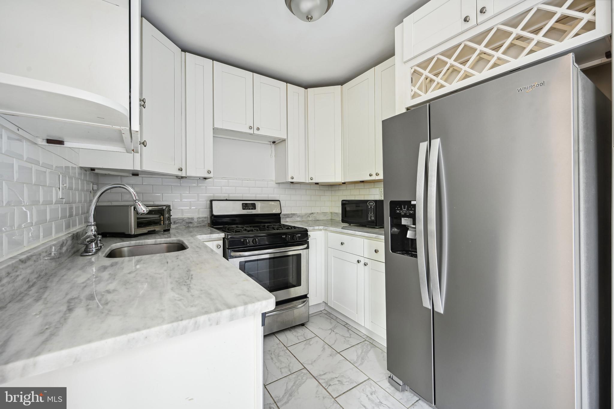 939 Longfellow Street Northwest, Unit 205 Washington, DC 20011 - Photo 4 of 16 a kitchen with stainless steel appliances granite countertop a refrigerator a sink and white cabinets