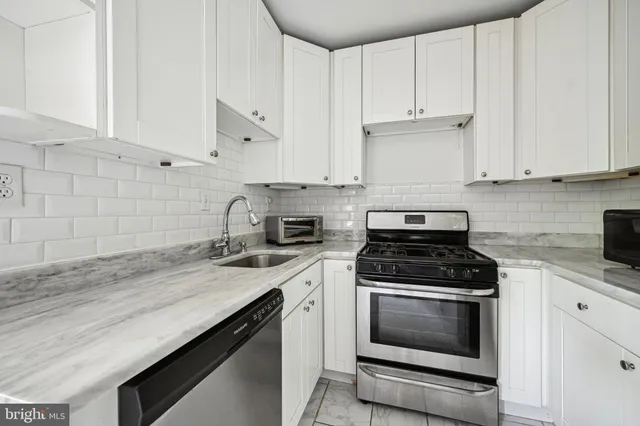 a kitchen with granite countertop white cabinets and black appliances