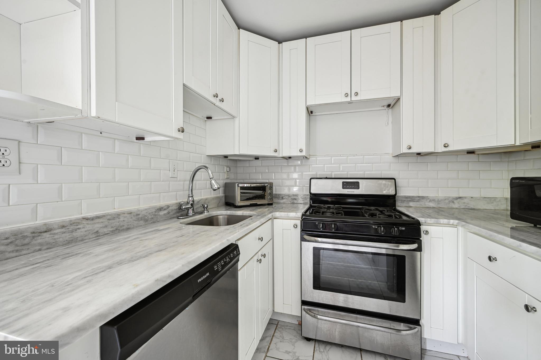 939 Longfellow Street Northwest, Unit 205 Washington, DC 20011 - Photo 5 of 16 a kitchen with granite countertop white cabinets and black appliances