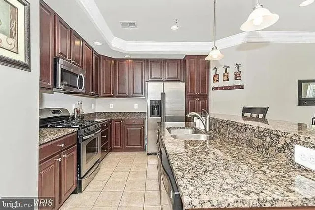 a kitchen with stainless steel appliances granite countertop a stove sink refrigerator and cabinets