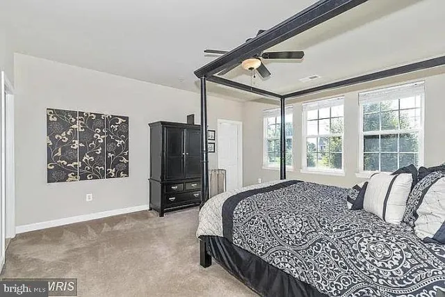 a bed sitting in a spacious bedroom next to a window