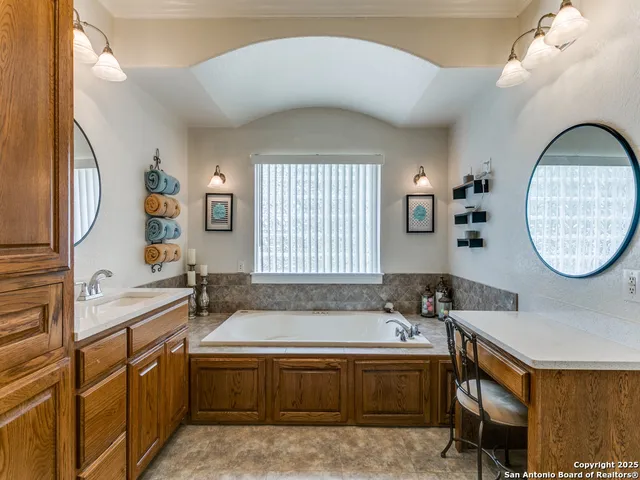 a spacious bathroom with a tub a double vanity sink a mirror and a window