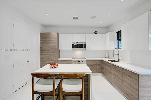 a kitchen with stainless steel appliances kitchen island granite countertop a dining table chairs and sink
