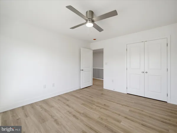 an empty room with wooden floor ceiling fan and windows