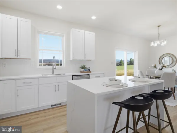 a kitchen with stainless steel appliances kitchen island a table chairs sink and cabinets
