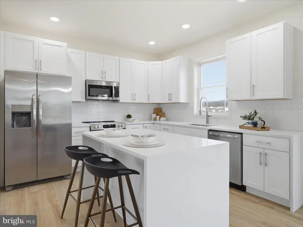 a kitchen with stainless steel appliances kitchen island a sink a stove a refrigerator and white cabinets