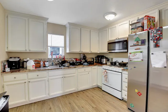 a kitchen with stainless steel appliances granite countertop a refrigerator sink and white cabinets