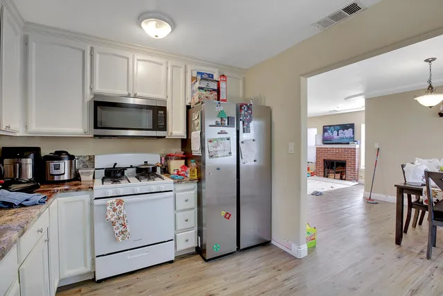 a kitchen with stainless steel appliances white cabinets and wooden floors