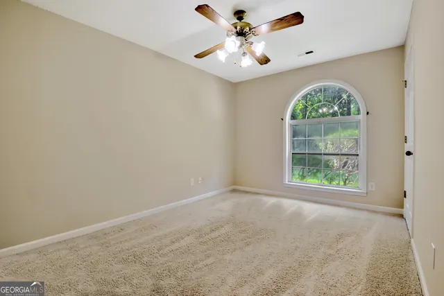 an empty room with a window and a fan