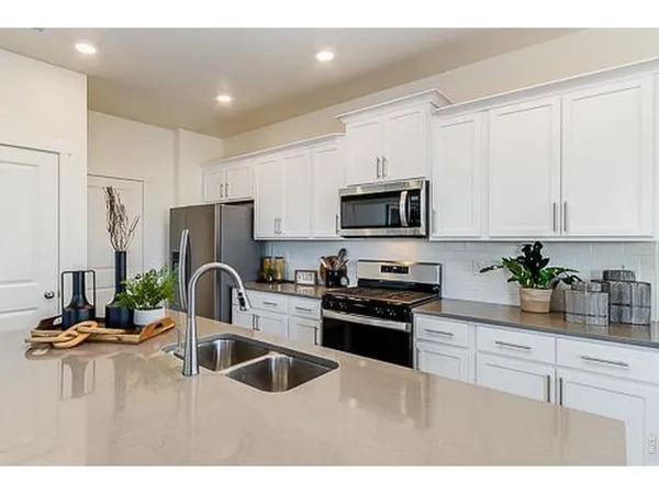 a kitchen with a sink a refrigerator and white cabinets