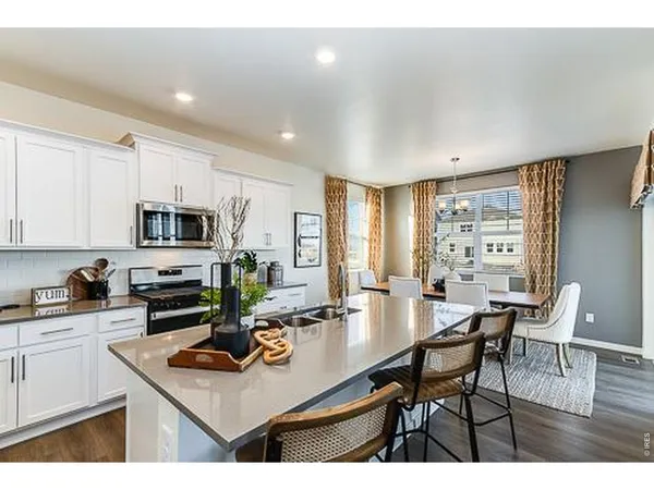 a kitchen with stainless steel appliances a table and chairs in it
