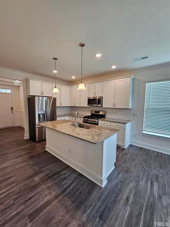 a large kitchen with stainless steel appliances kitchen island a large counter top and wooden floors