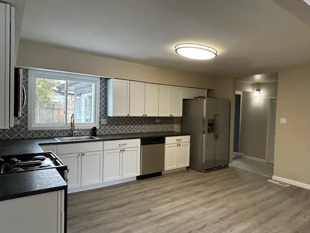 a kitchen with granite countertop stainless steel appliances a sink cabinets and wooden floor