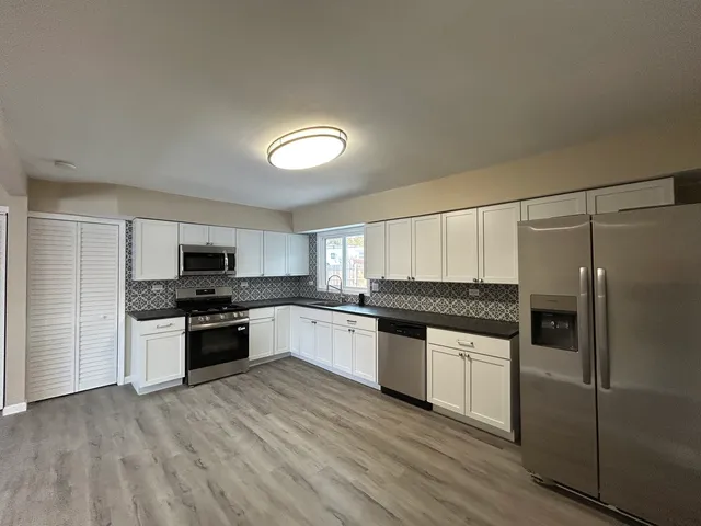 a kitchen with granite countertop a refrigerator and a stove top oven