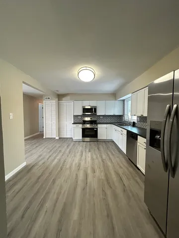 a kitchen with a refrigerator and white cabinets