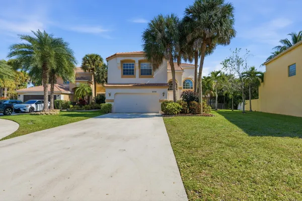 a front view of a house with a yard and palm tree