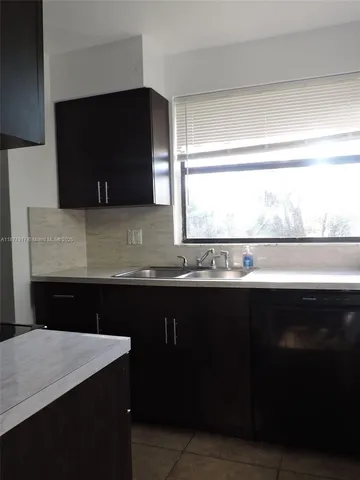 a kitchen with a sink a microwave a stove and black cabinets