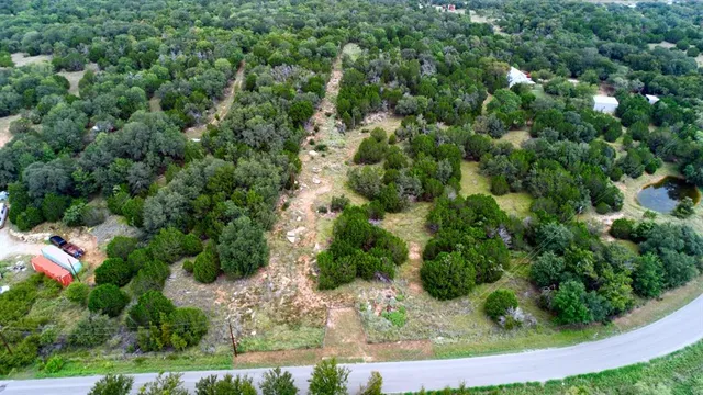 an aerial view of residential house with outdoor space and trees all around