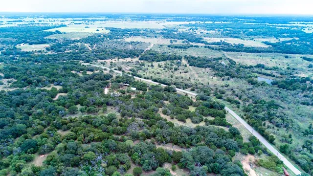 an aerial view of residential houses with outdoor space and trees