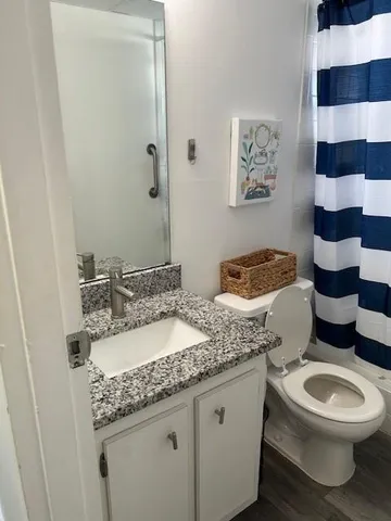 a bathroom with a granite countertop toilet sink and mirror