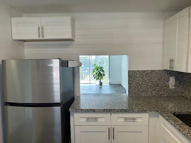 a kitchen with granite countertop a refrigerator and a sink