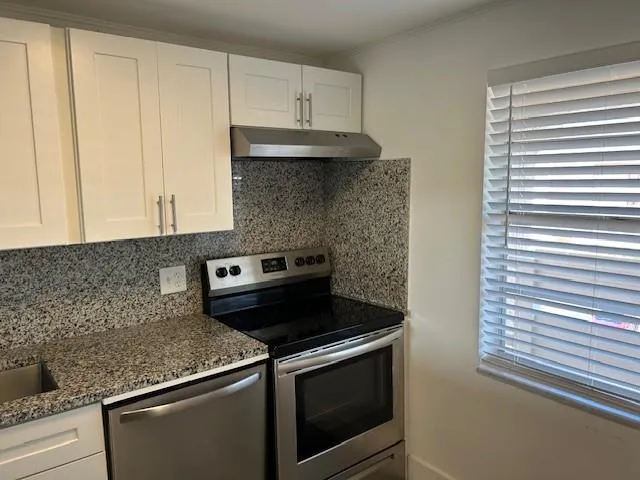 a kitchen with granite countertop a stove sink and cabinets