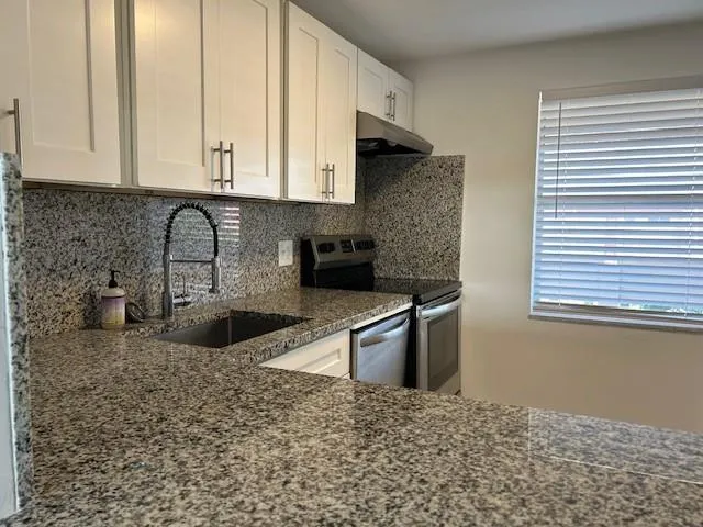 a kitchen with stainless steel appliances granite countertop a sink stove and granite counter tops