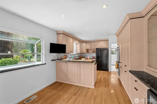 a kitchen with stainless steel appliances granite countertop a refrigerator a sink dishwasher a stove and a flat screen tv