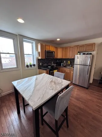 a kitchen with a table chairs refrigerator and wooden floor