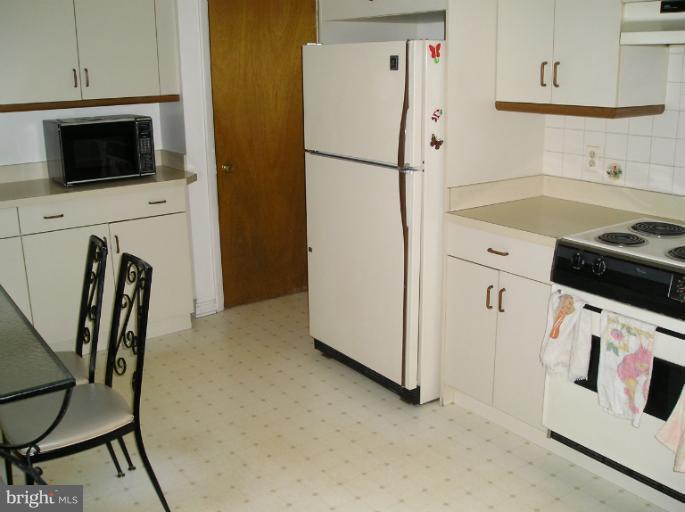 6813 Queens Ferry Road Baltimore, MD 21239 - Photo 13 of 19 a kitchen with a refrigerator a stove a microwave and cabinets