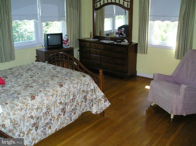 6813 Queens Ferry Road Baltimore, MD 21239 - Photo 6 of 19 a bedroom with a bed and wooden floor