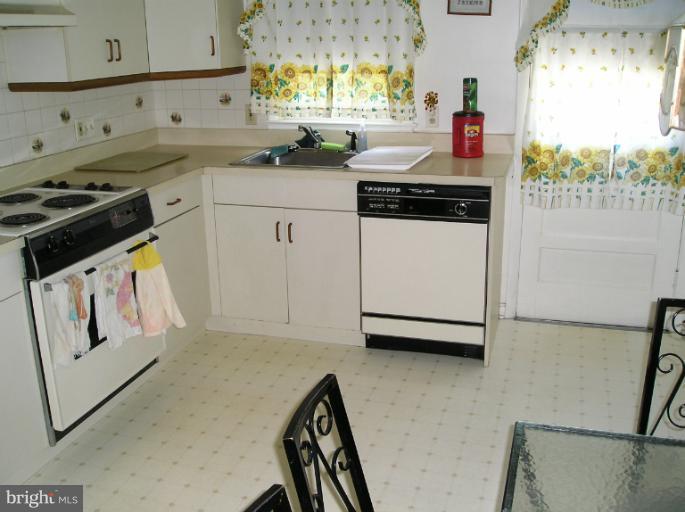 6813 Queens Ferry Road Baltimore, MD 21239 - Photo 10 of 19 a kitchen with granite countertop white cabinets and white appliances