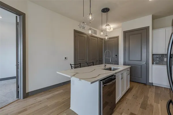 a kitchen that has a sink a microwave oven a refrigerator and wooden floor