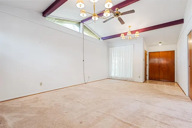 an empty room with ceiling fan and window