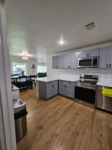a kitchen with stainless steel appliances kitchen island granite countertop a sink cabinets and wooden floor