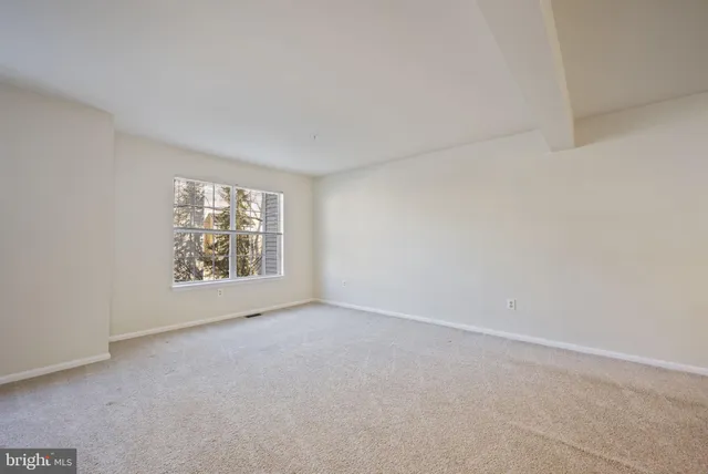 an empty room with windows and ceiling fan